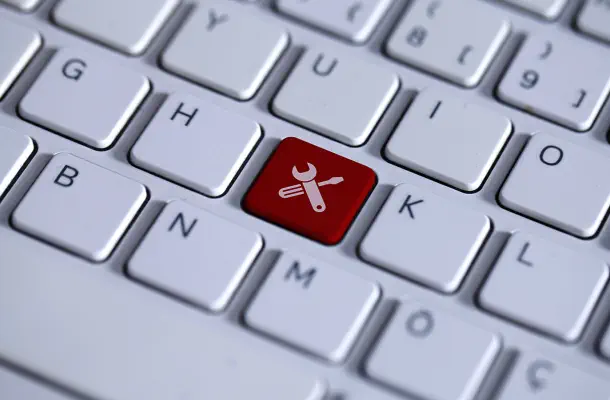 Foto einer weißen Tastatur mit einer roten Taste in der Mitte. Auf der roten Taste ist ein Icon von sich kreuzenden Schraubenschlüssel und Schraubendreher.